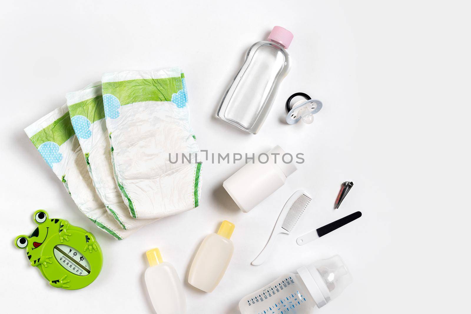 Babies goods diaper, baby powder, cream, shampoo, oil on white background with copy space. Top view or flat lay. Maternity concept