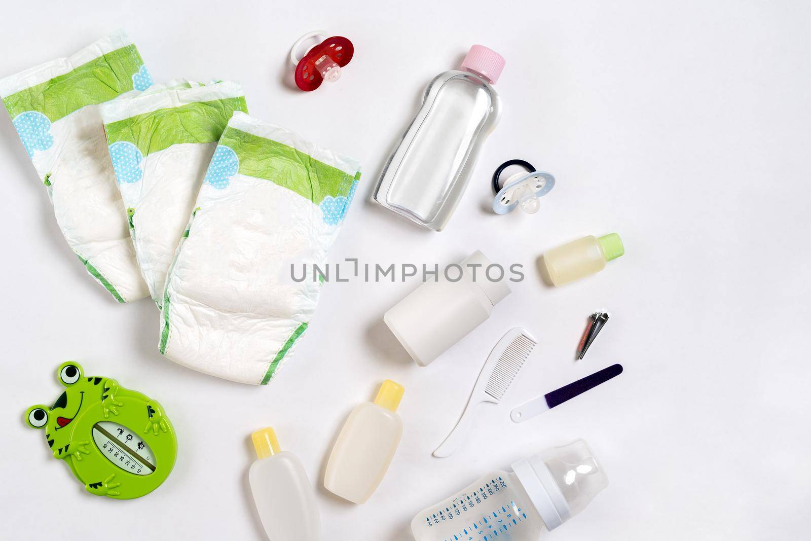 Babies goods diaper, baby powder, cream, shampoo, oil on white background with copy space. Top view or flat lay. Maternity concept