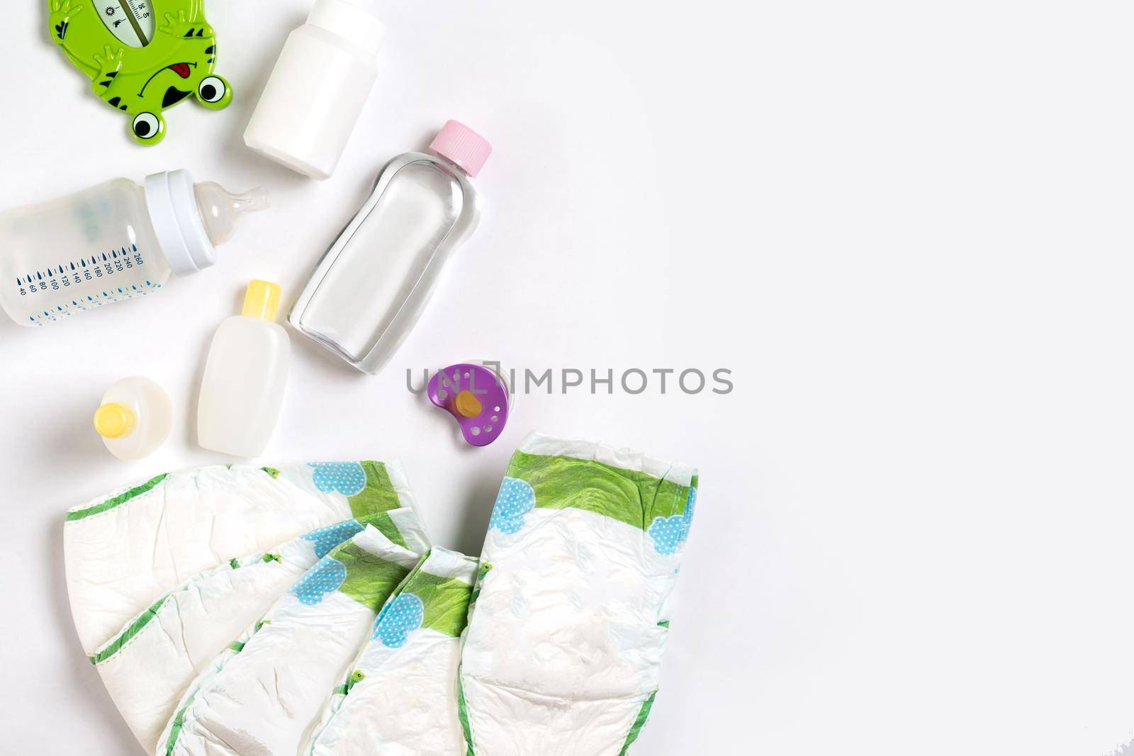 Babies goods diaper, baby powder, cream, shampoo, oil on white background with copy space. Top view or flat lay. Maternity concept