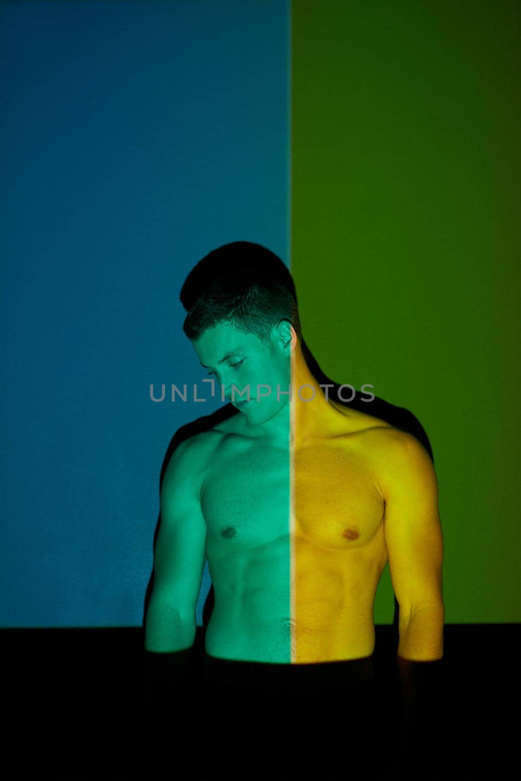 The light eventually exposes what you want to hide. Studio shot of a young man posing against abstract lighting. by YuriArcurs