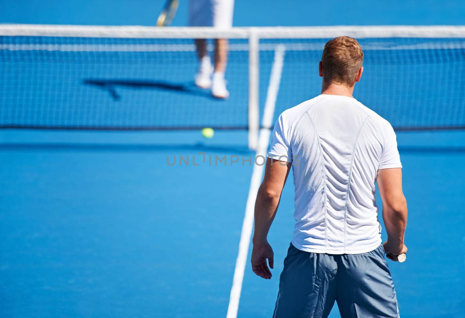 Showing up to every tennis practice. Shot of two people playing tennis outside. by YuriArcurs