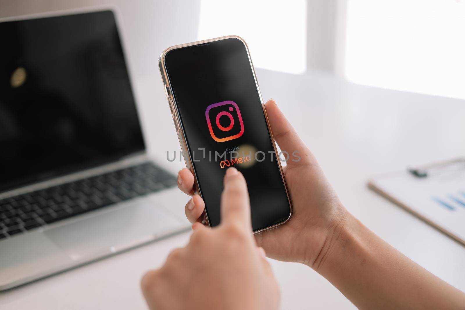 CHIANG MAI, THAILAND - MAR 06 2022: A woman holds Apple iPhone 13 with Instagram application from meta on the screen at cafe. Instagram is a photo-sharing app for smartphones.