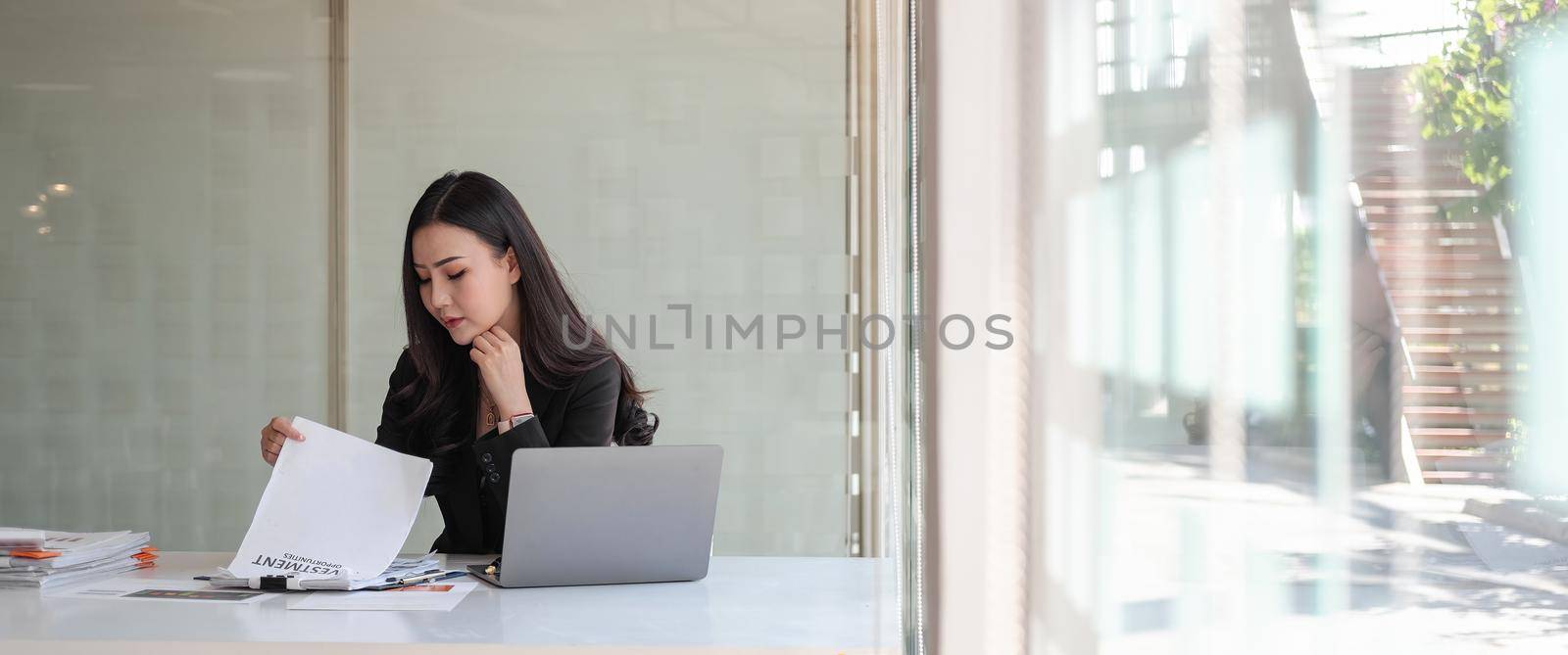 Crop shot of business asian woman investment consultant analyzing company annual financial report balance sheet statement working with documents graphs.