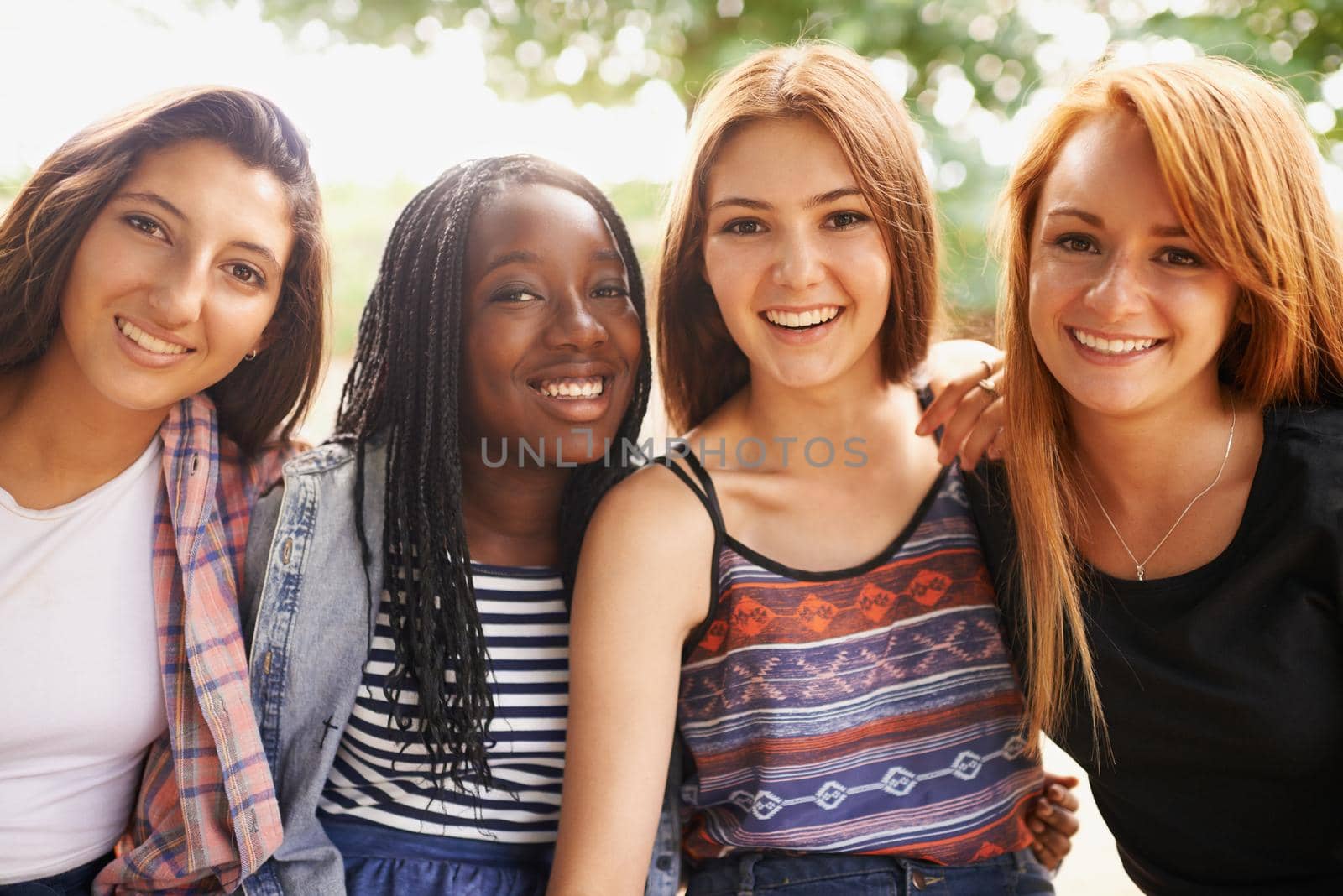 Theyre the rainbow of this nation. Four beautiful young girls smiling happinly while they sit outside. by YuriArcurs