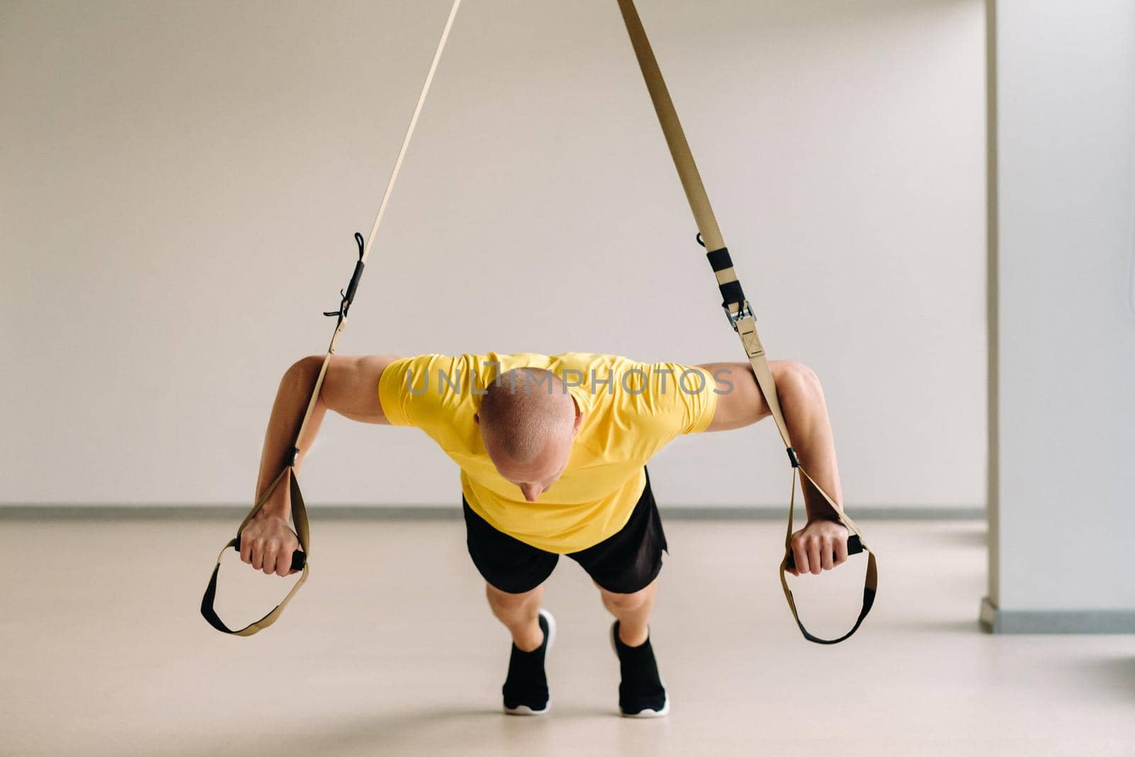 A focused male athlete performing an exercise on functional loops in the gym.