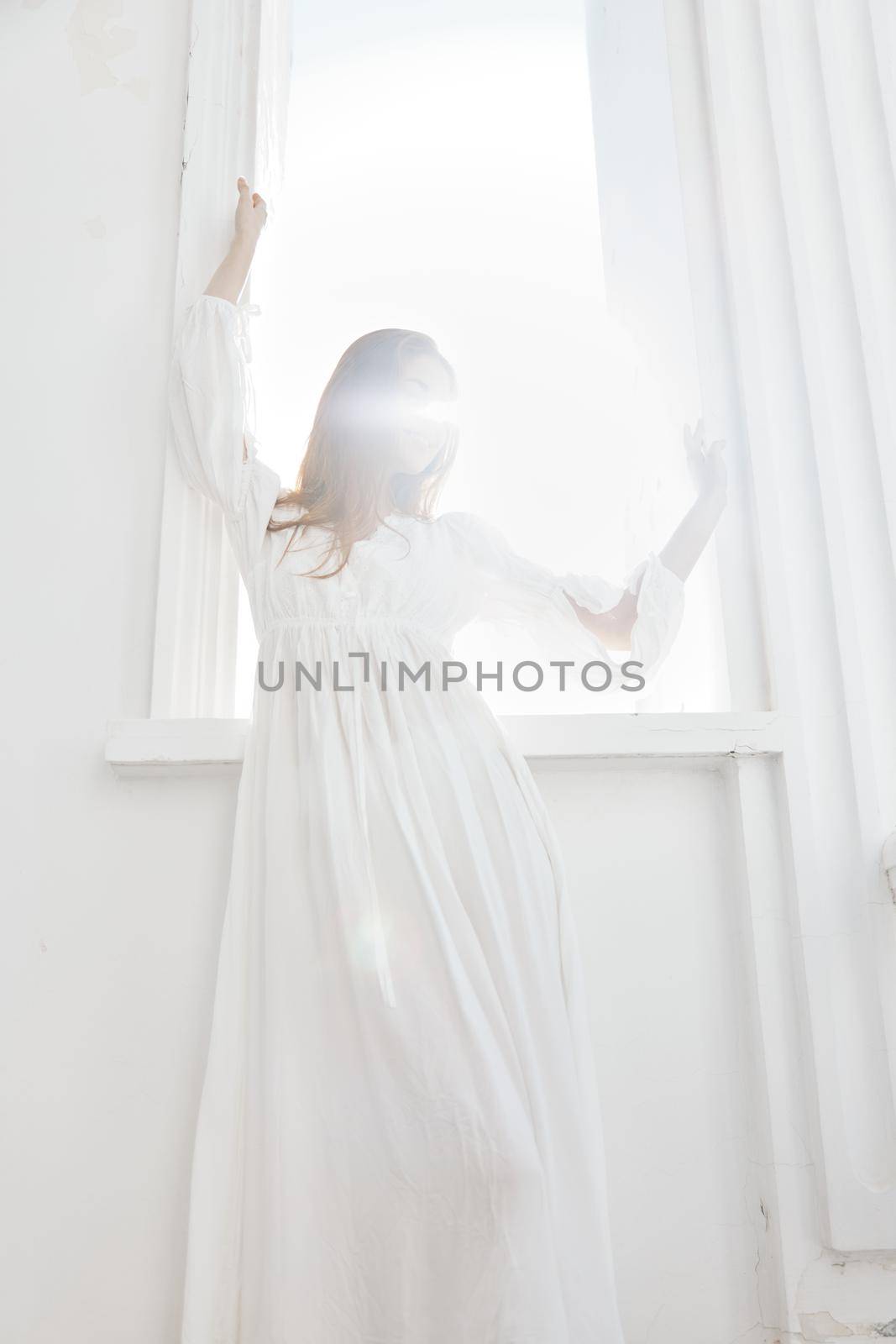 Woman in white dress near window posing romance of the sun by SHOTPRIME