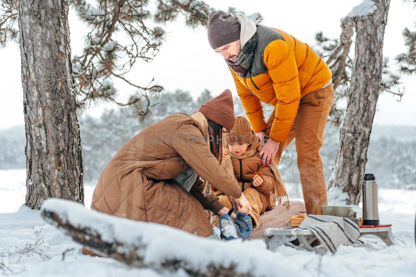 Happy family with cups of hot tea spending time together in winter forest, close up