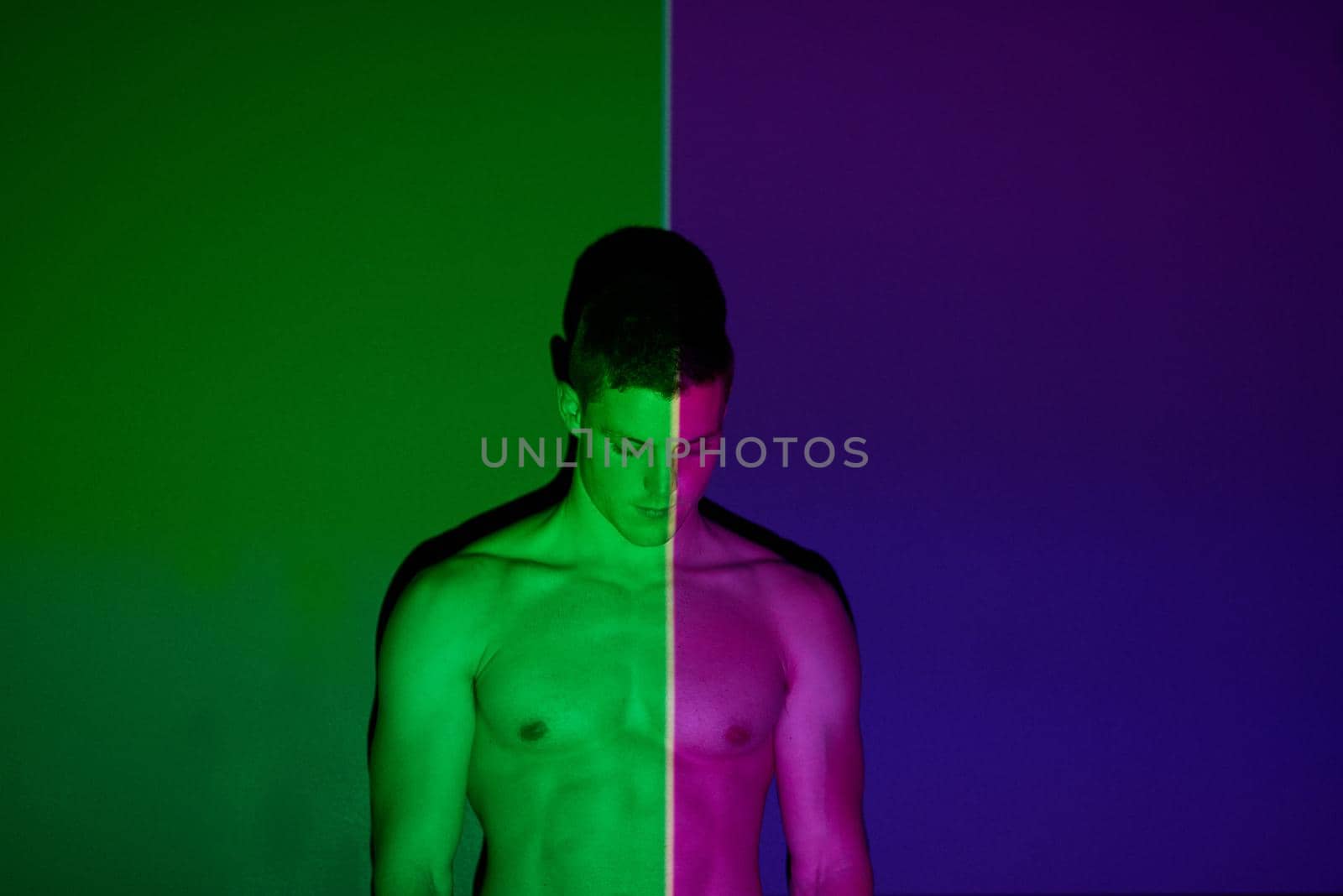 Theres two sides to all of us. Studio shot of a young man posing against abstract lighting. by YuriArcurs