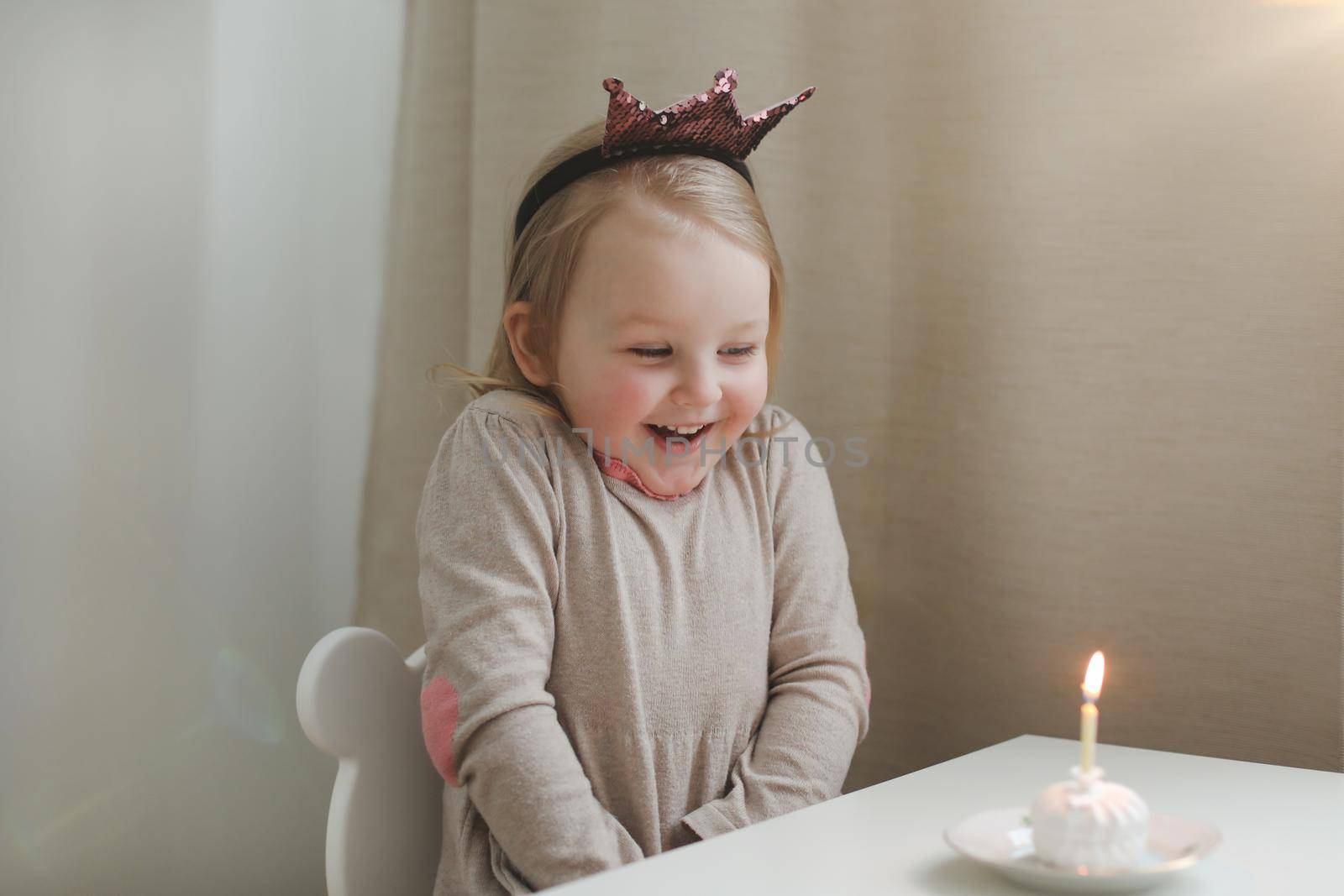 Cute beautiful little baby girl celebrating first birthday. Child blowing one candle on homemade baked cake, indoor. Birthday family party for lovely toddler child, beautiful happy daughter