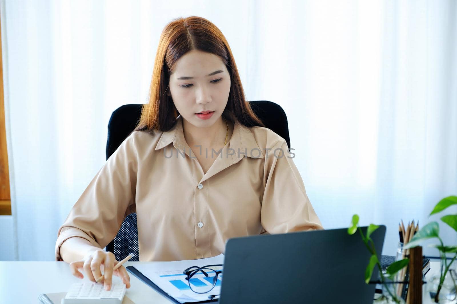 A young woman uses computers and calculators to work from home to avoid the risk of contracting the coronavirus in her workplace