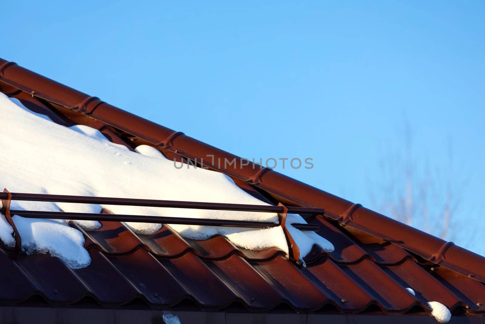 Melting snow on the metal roof and blue sky above