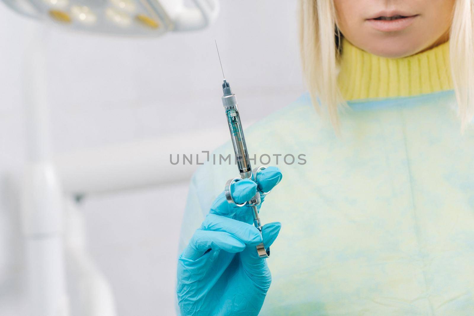 The dentist holds an injection syringe for the patient in the office.