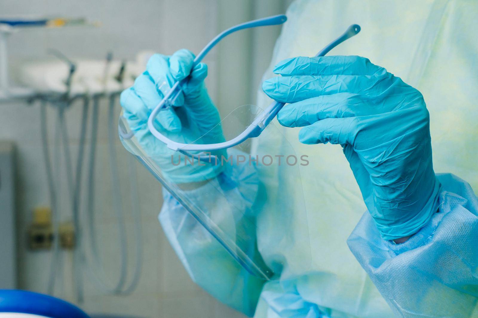 close up of a dentist's hands holding a protective plastic screen in his office.