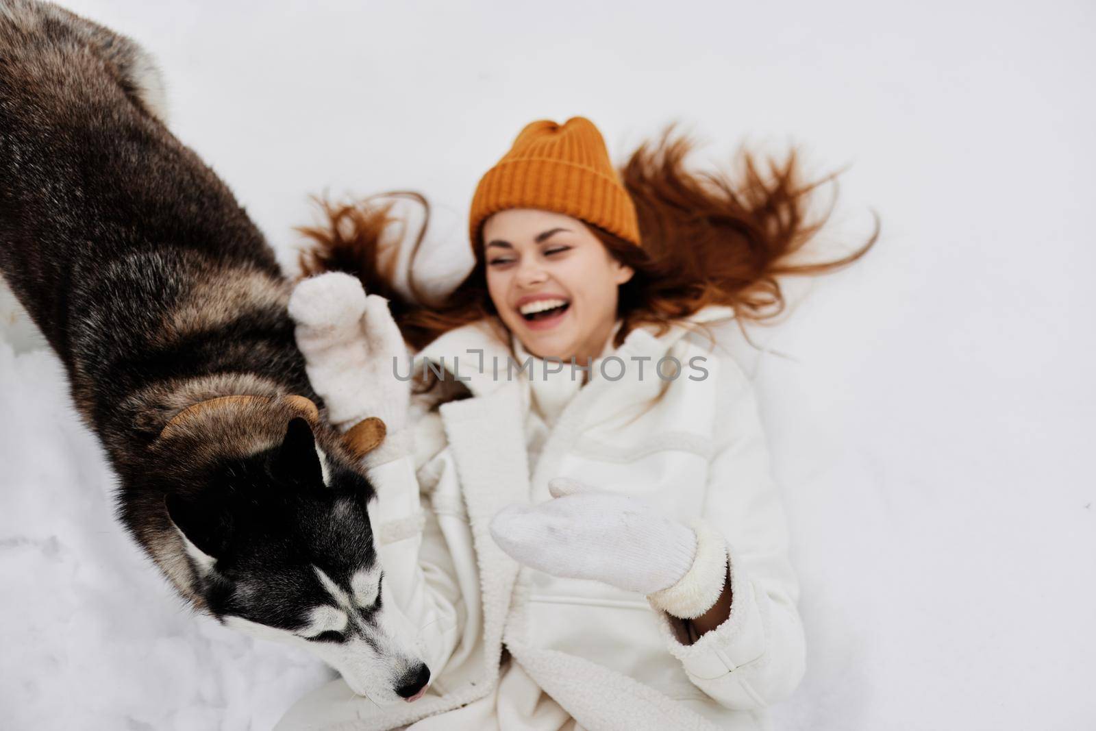 young woman in the snow playing with a dog fun friendship winter holidays. High quality photo