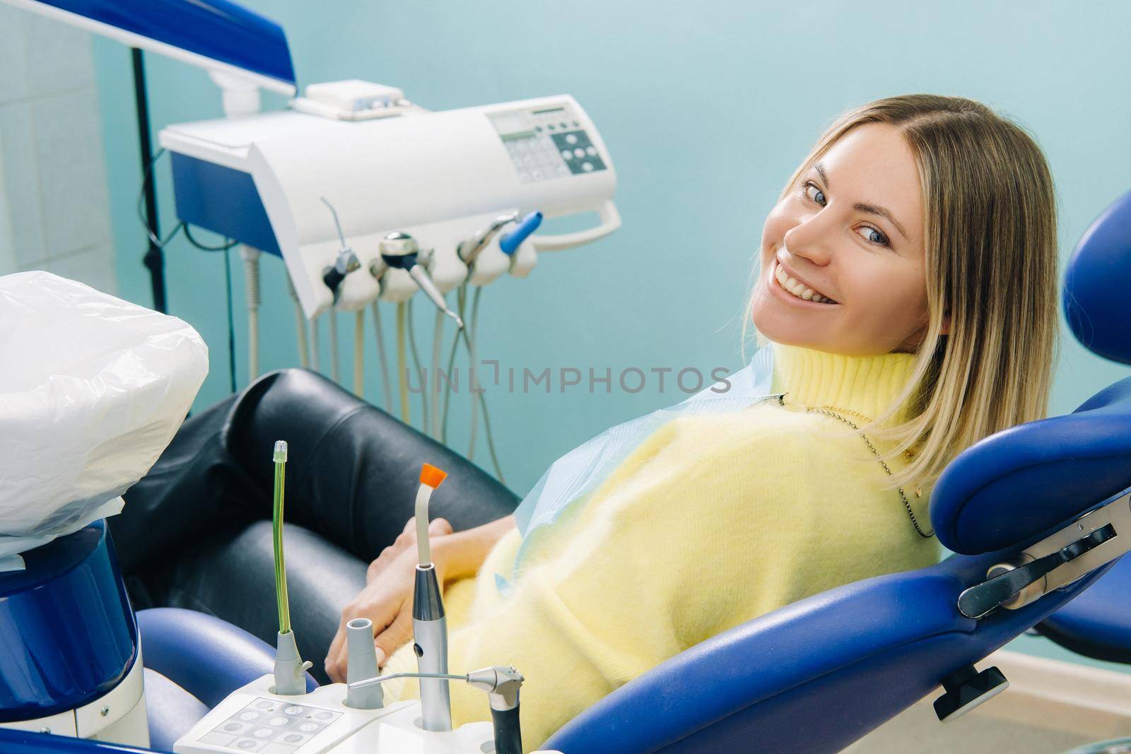 A beautiful girl patient smiles sitting in a dentist's chair.
