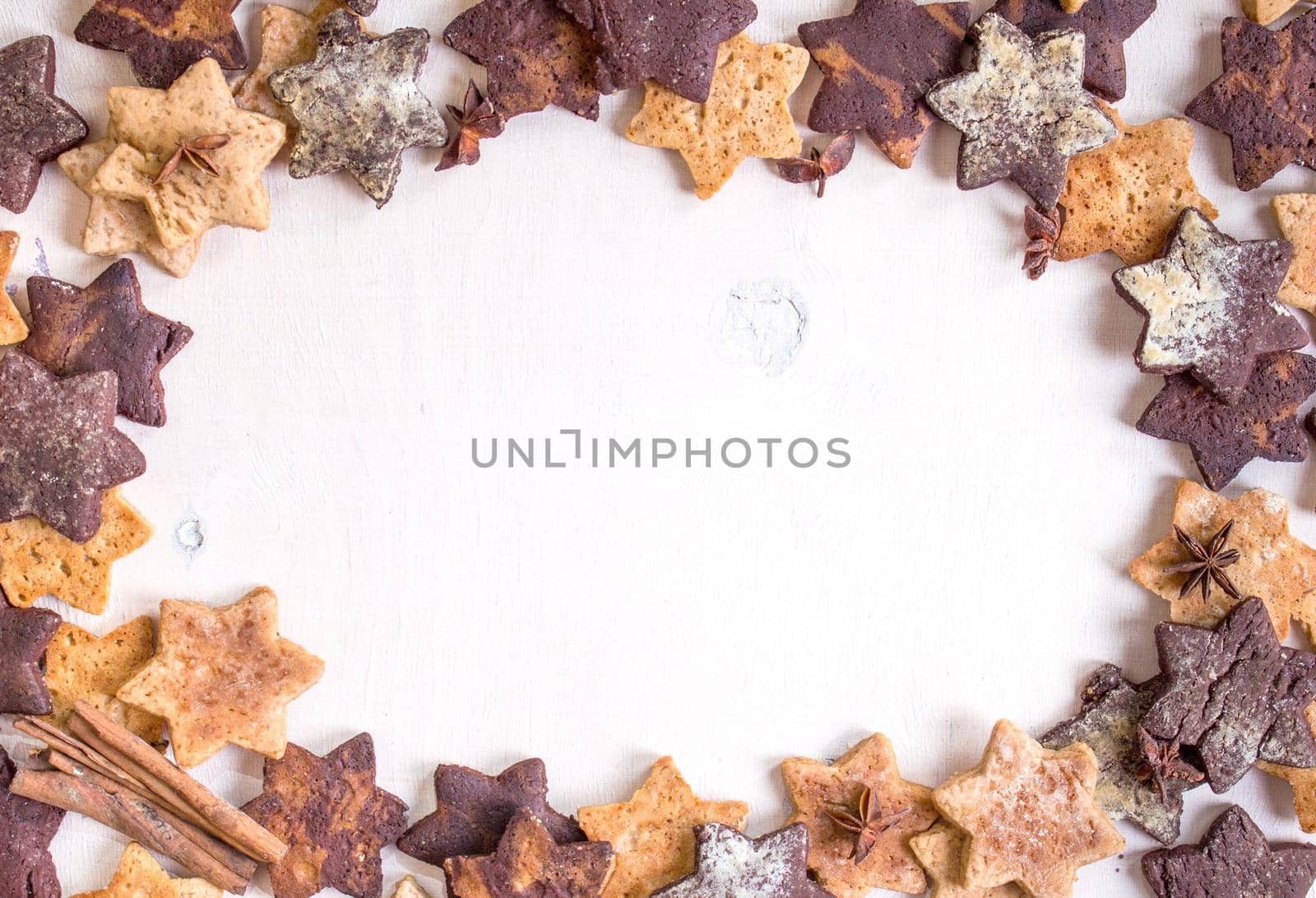 Assorted christmas ginger cookies with cinnamon sticks, pinecones over white wooden table. Christmas cooking background. Six pointed star cookies