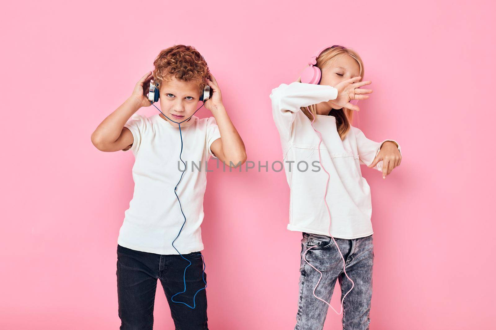 Active young people stand next to in headphones pink color background. High quality photo