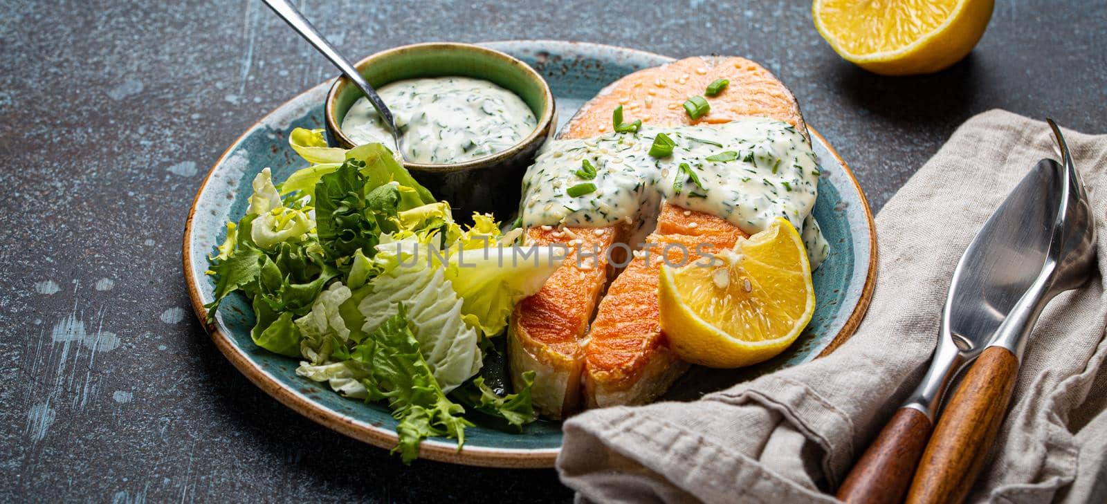 Healthy food meal cooked grilled salmon steak with white dill sauce and green salad leafs by its_al_dente