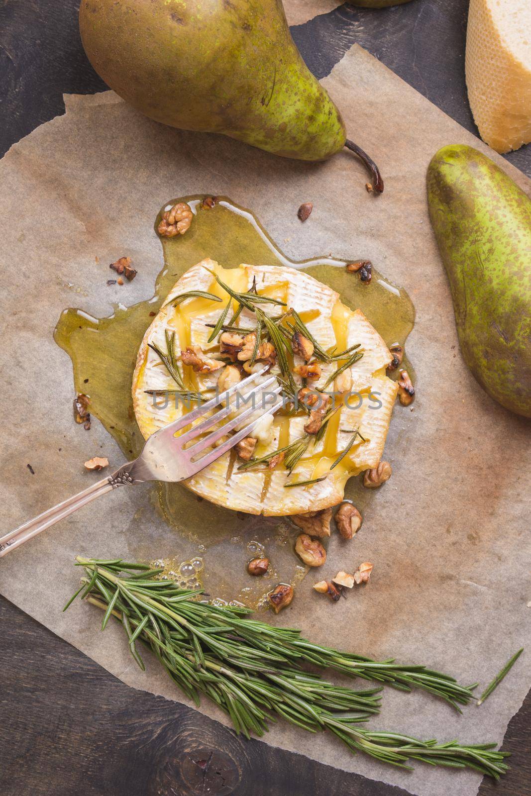 Delicious beautiful baked camembert with fork. Cheese with honey, walnuts, herbs and pears