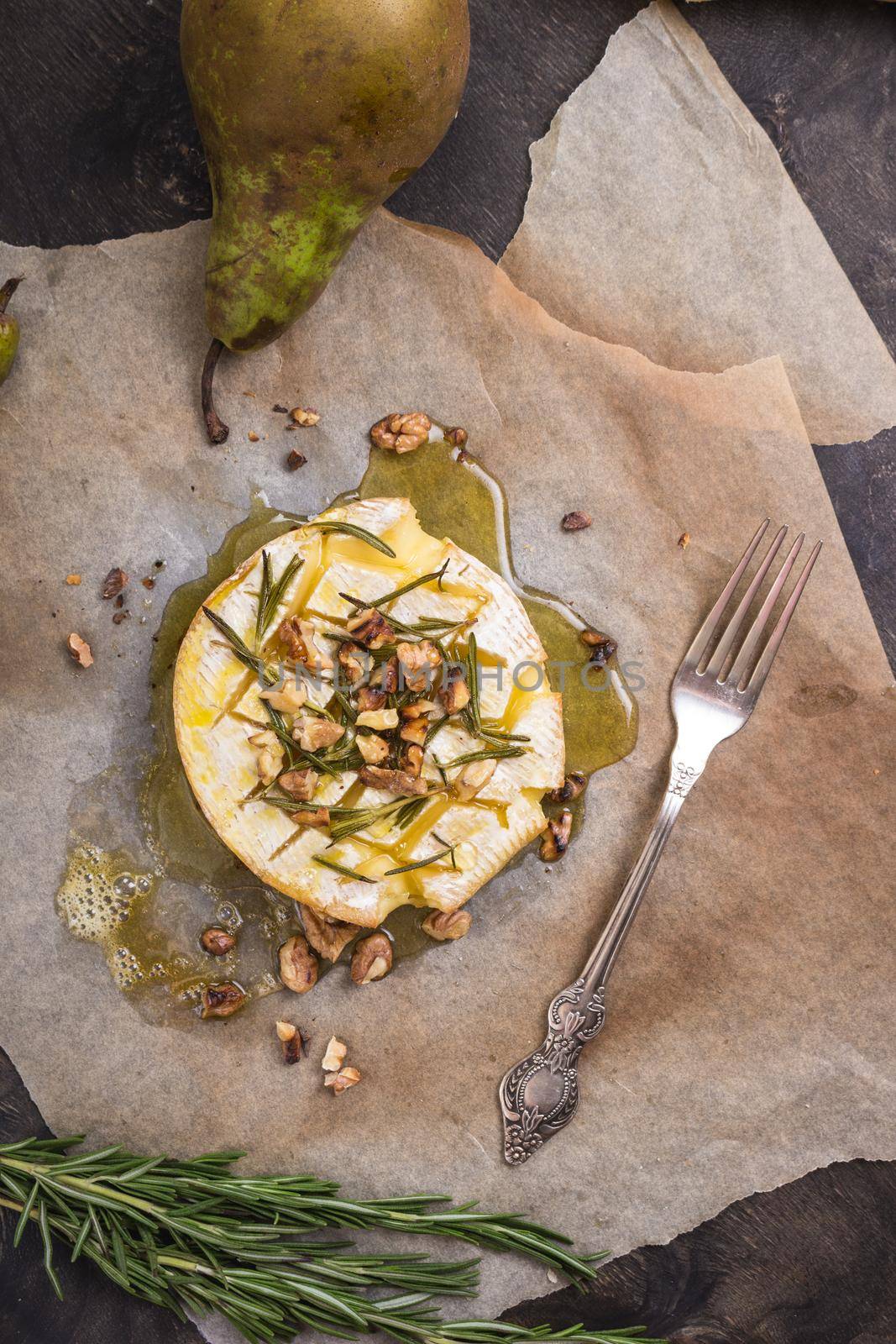 Delicious beautiful baked camembert with honey, walnuts, herbs and pears