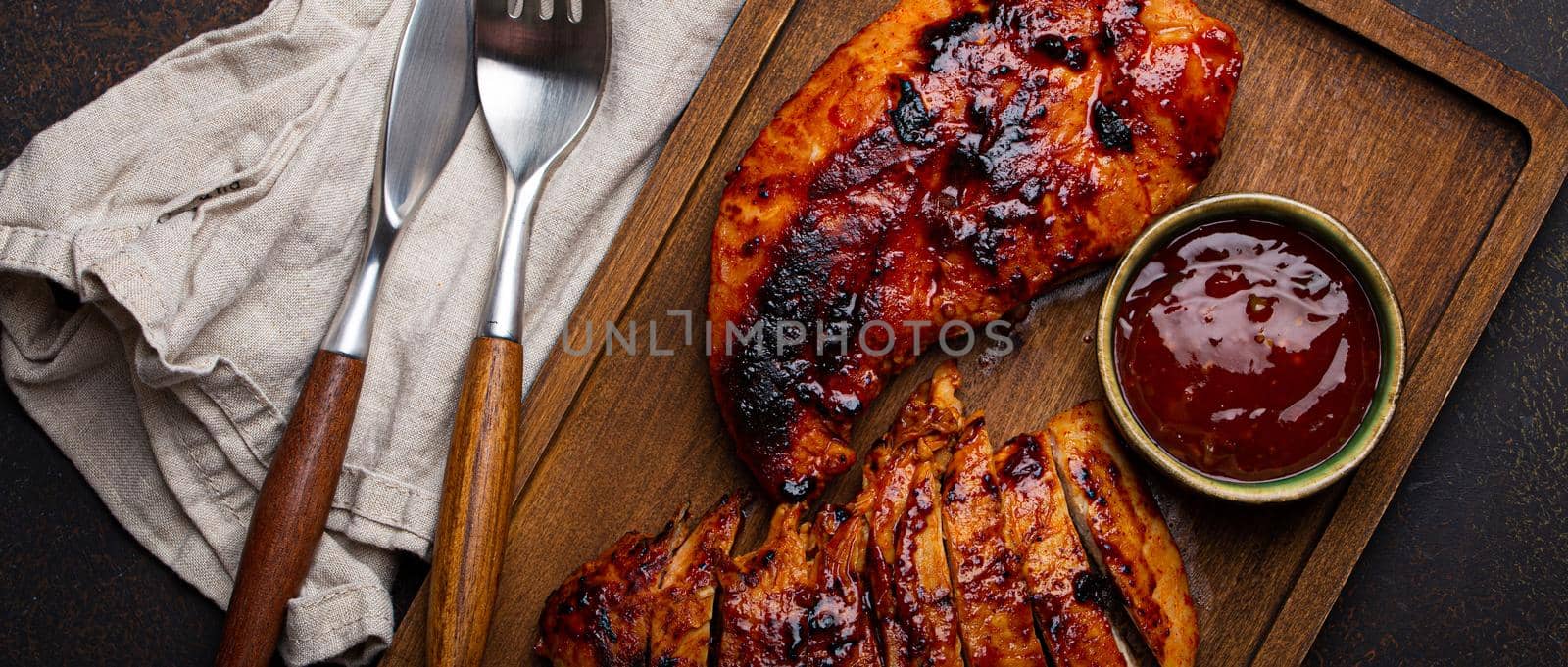 Grilled turkey or chicken fillet with red sauce served and sliced on wooden cutting board by its_al_dente