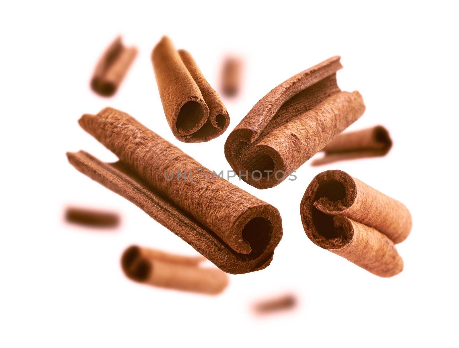 Cinnamon sticks levitate on a white background.