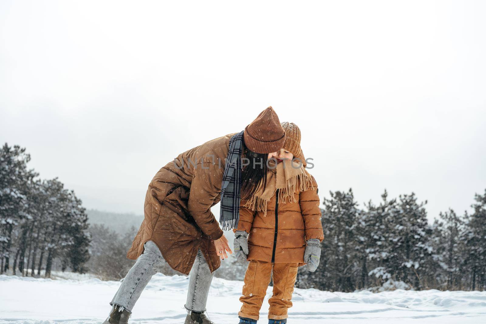 Woman with a little son on a winter hike in the snowy forest together