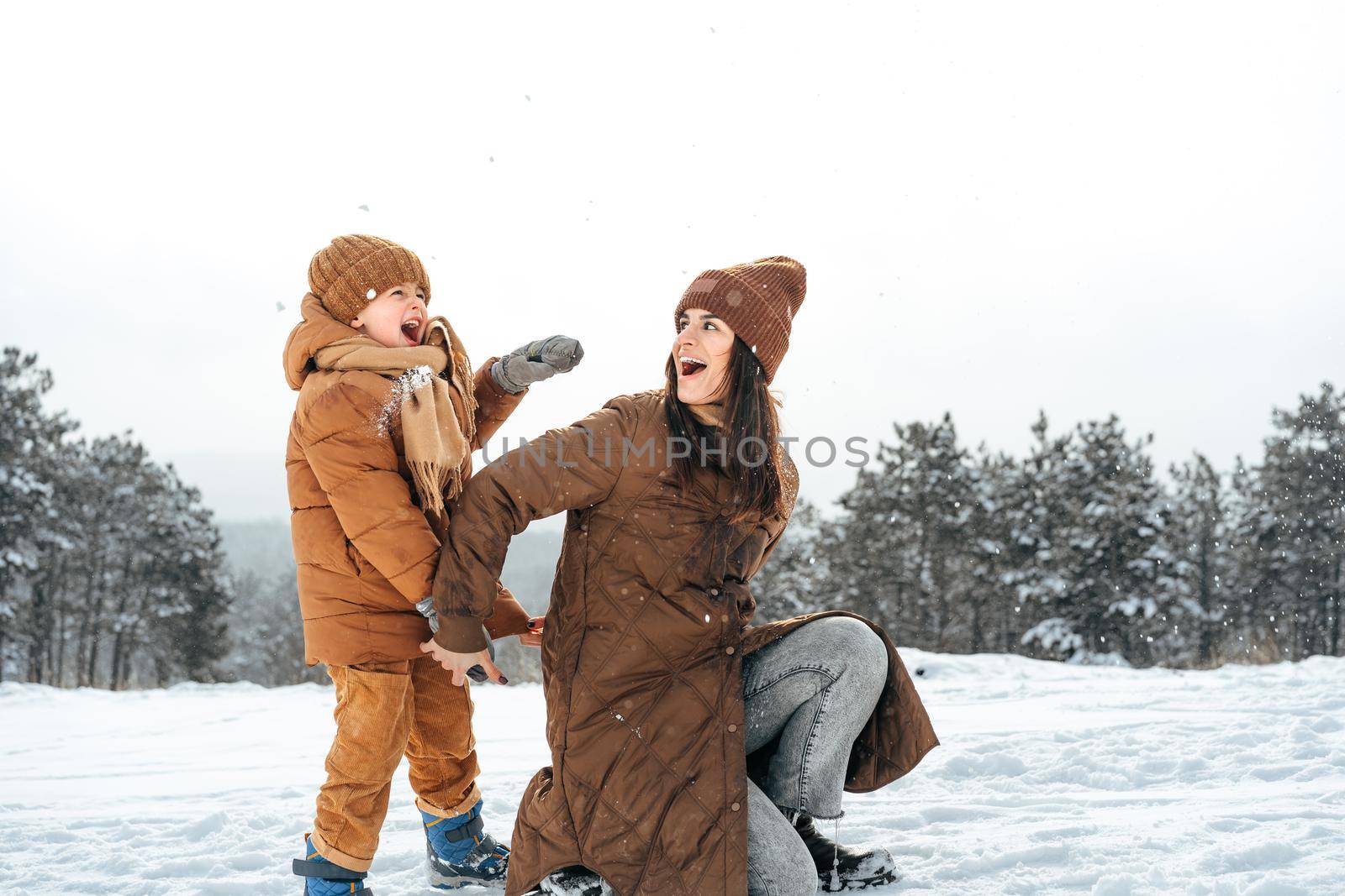 Woman with a little son on a winter hike in the snowy forest together