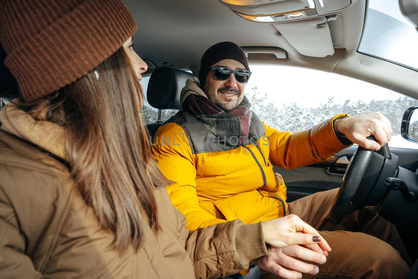 Family couple sitting in car in winter clothes iin snow forest, close up