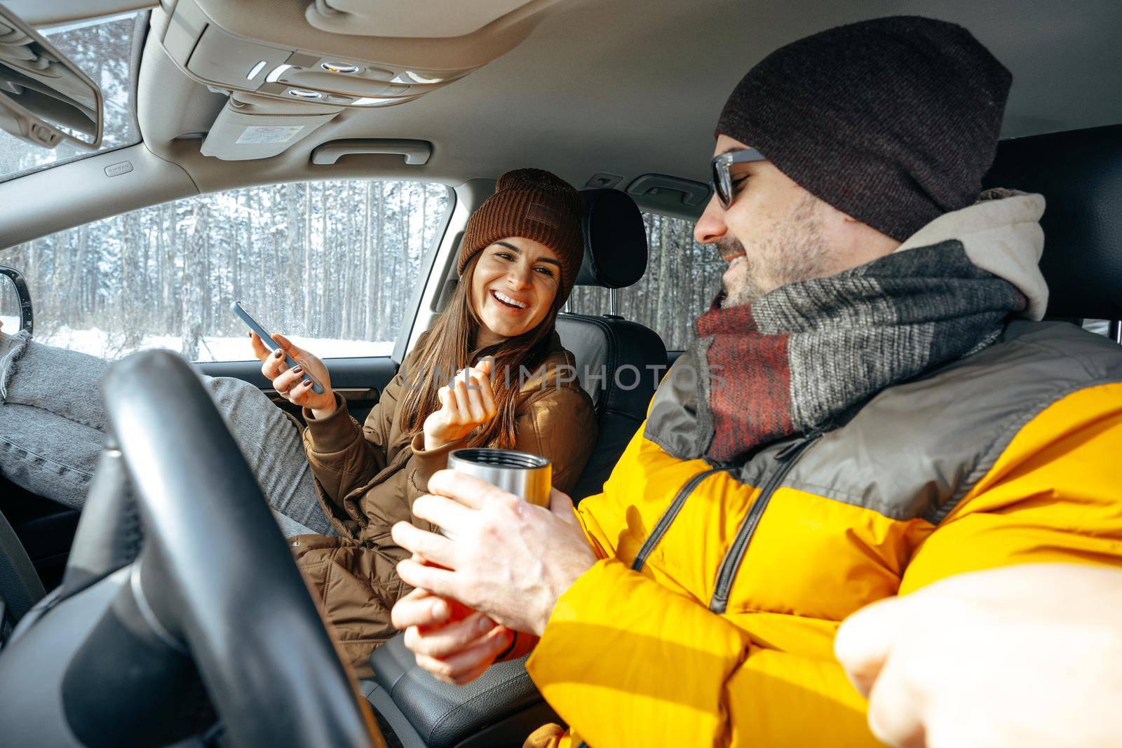 Family couple sitting in car in winter clothes iin snow forest, close up