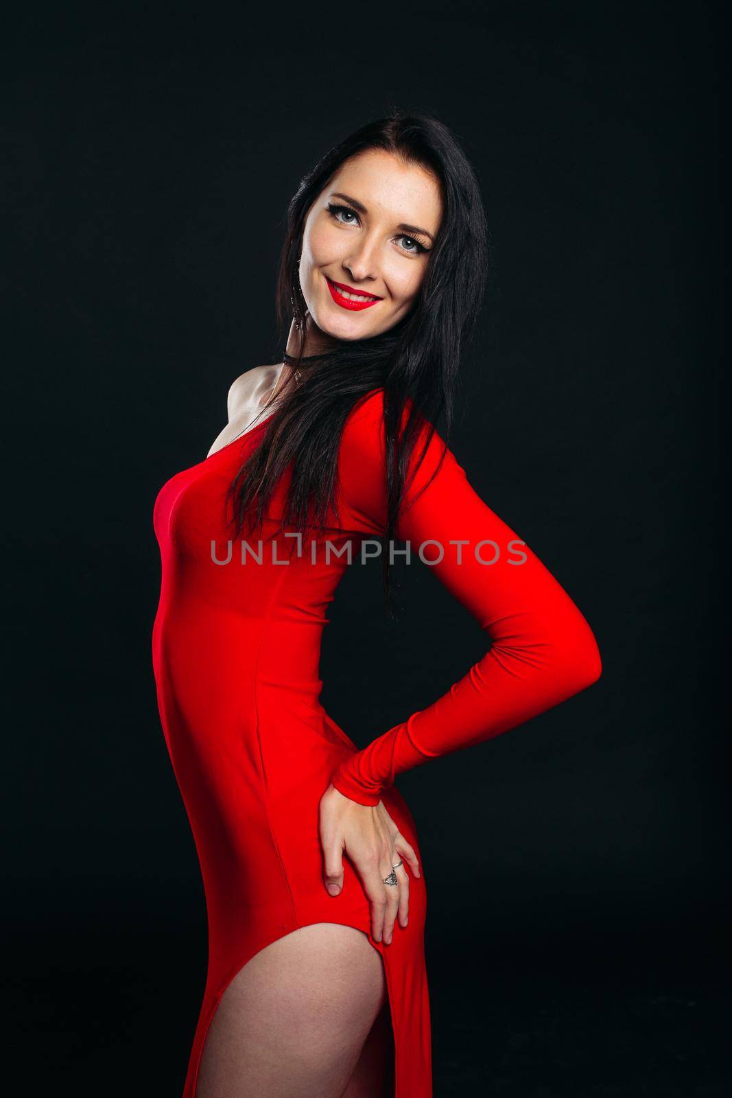 Studio portrait of sexy and beautiful girl in glamour red dress posing at gray studio. Gorgeous brunette woman before dancing party. Female after beauty salon. Copy space.