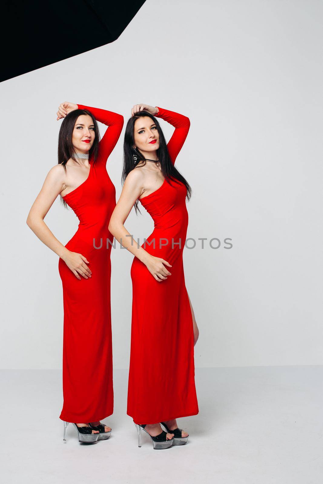 Two sexy sisters twins in red dresses. by StudioLucky