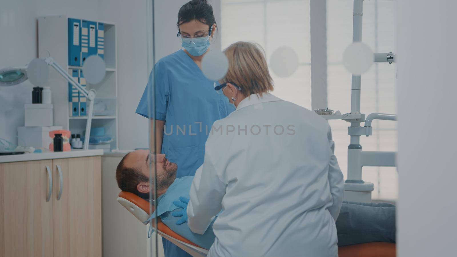 Medic and nurse examining teeth after oral care procedure with dental tools. Stomatologist and nurse looking at surgery results to cure toothache and caries problems. Dentistry checkup