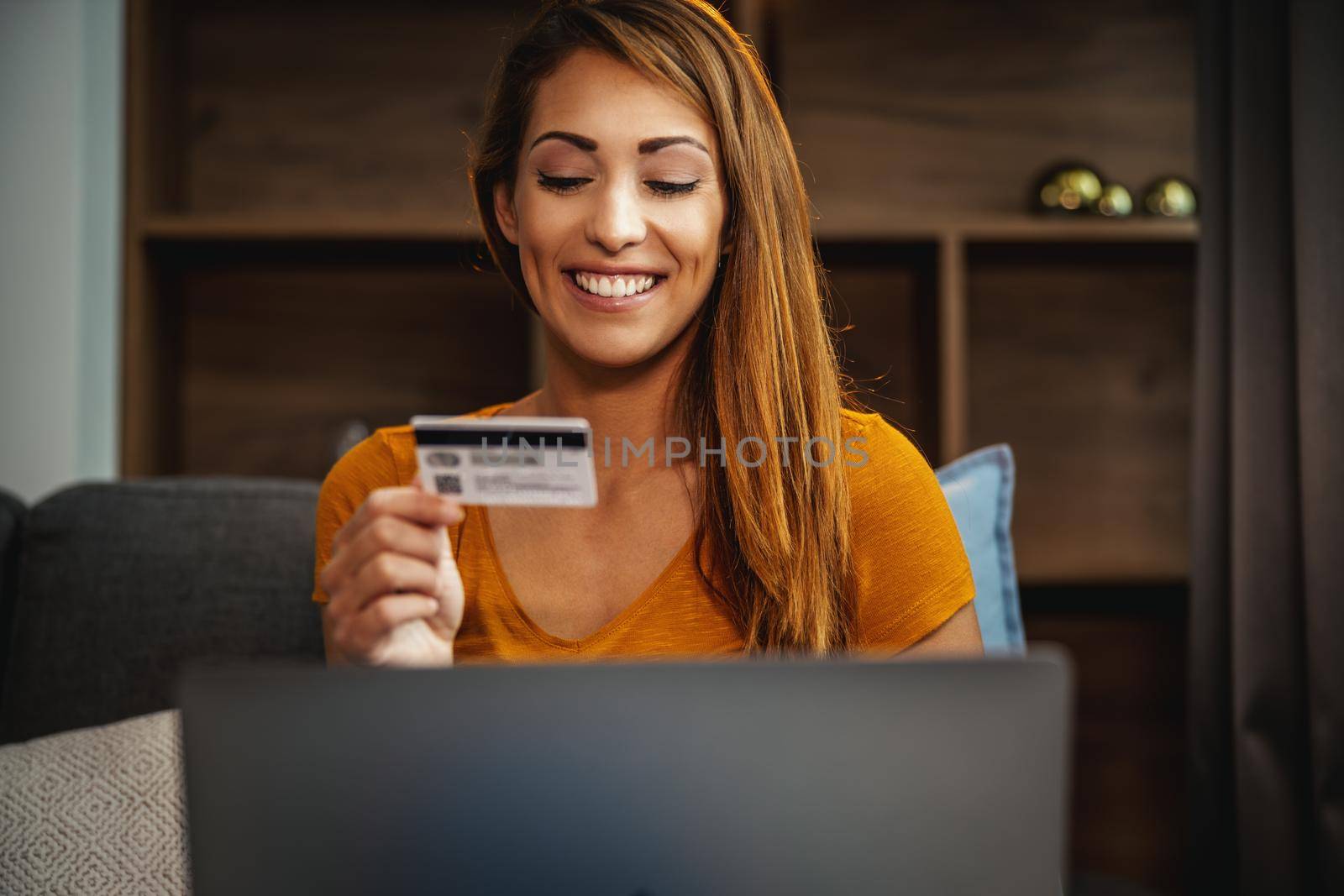 Shot of a beautiful young woman doing online shopping on her laptop while sitting on the sofa at home.