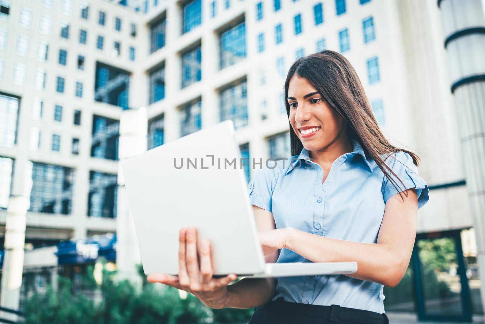 Emotional portrait of a happy and beautiful young businesswoman who working on laptop on the background of a business center.