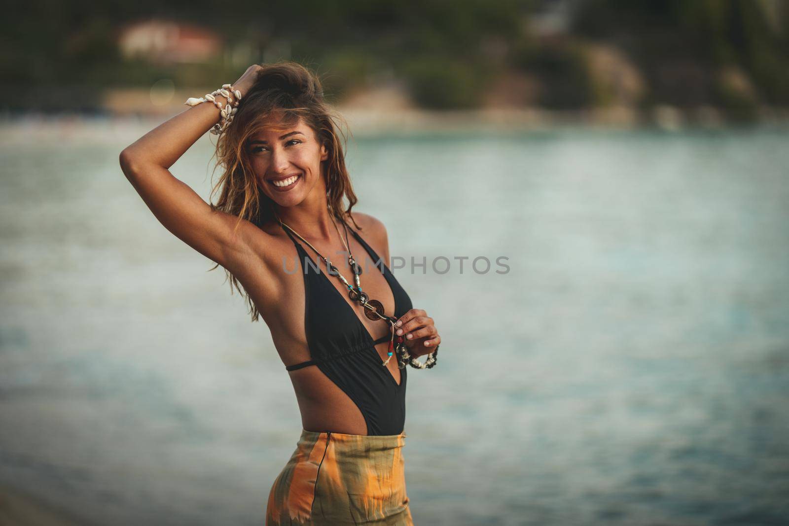 A beautiful young woman is having fun and relaxing on the beach at the sunset. 