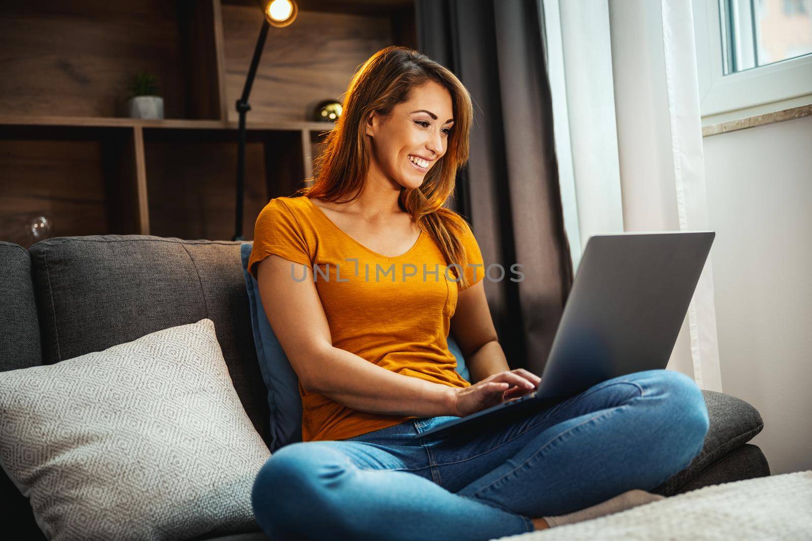 Shot of an attractive young woman sitting cross legged on the sofa and using her laptop at home.