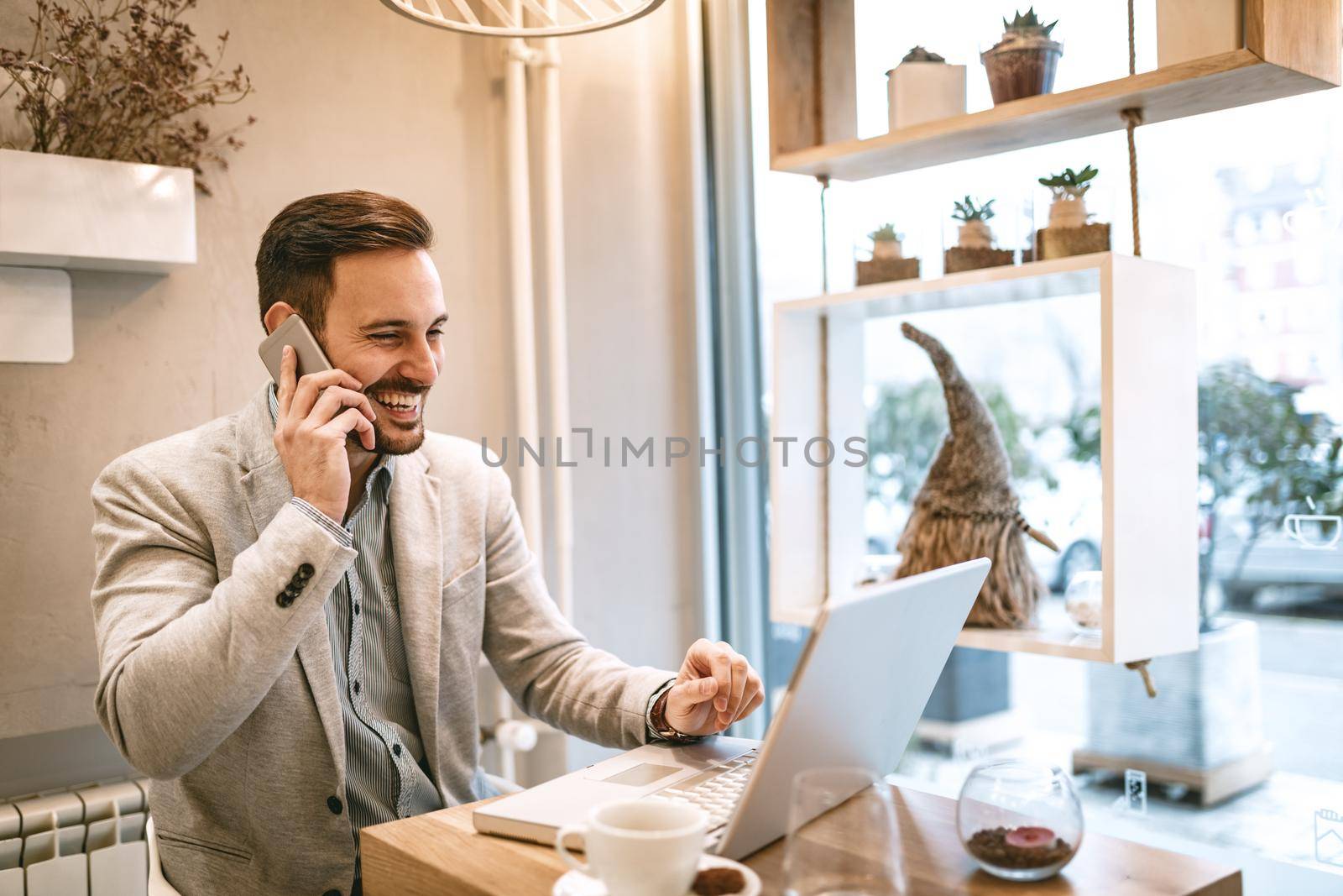 Young businessman on a break in a cafe. He is working at laptop and using smartphone. 