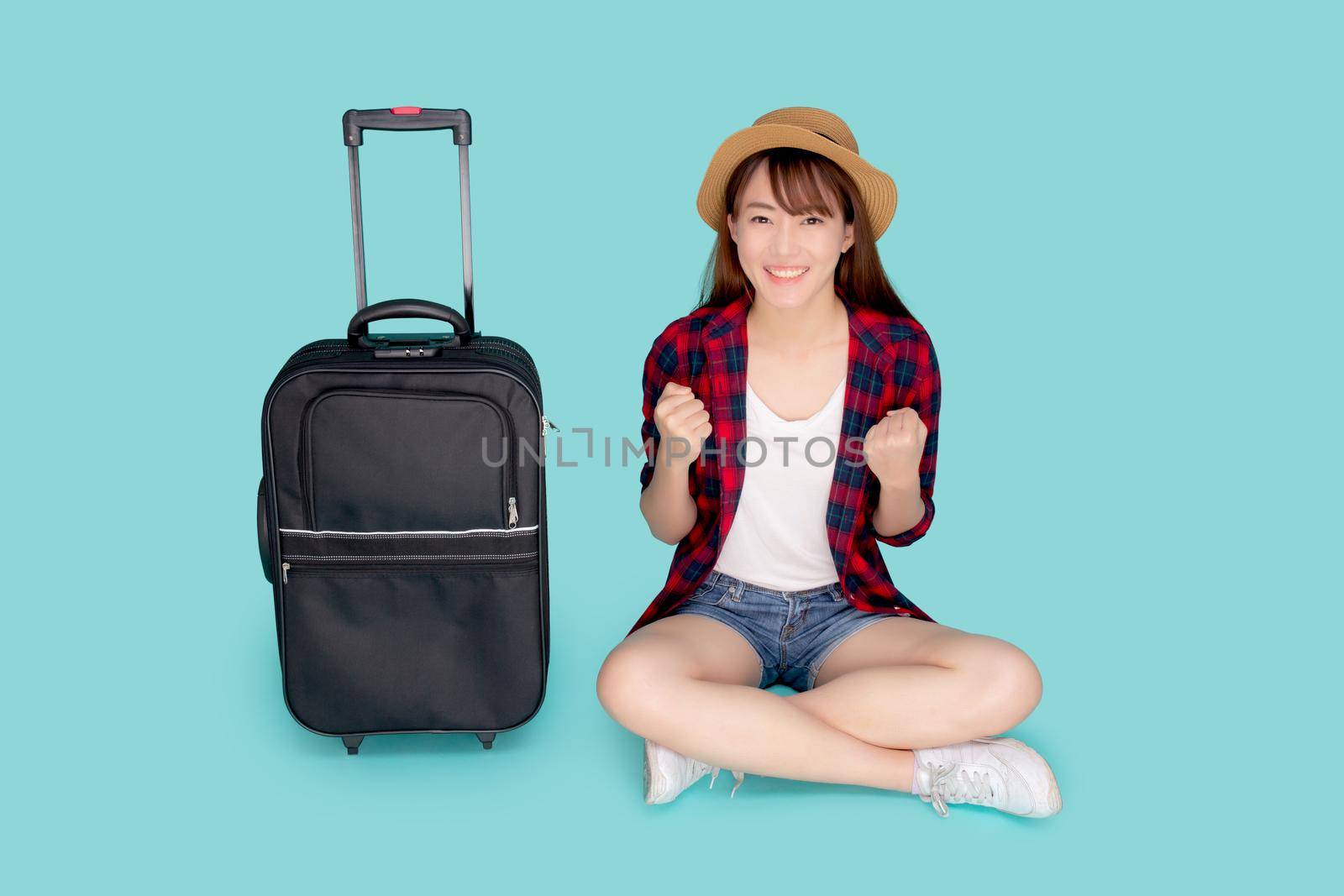 Beautiful portrait young asian woman excited and success and luggage for travel trip in summer vacation isolated on blue background, asia girl sitting and suitcase for journey concept.