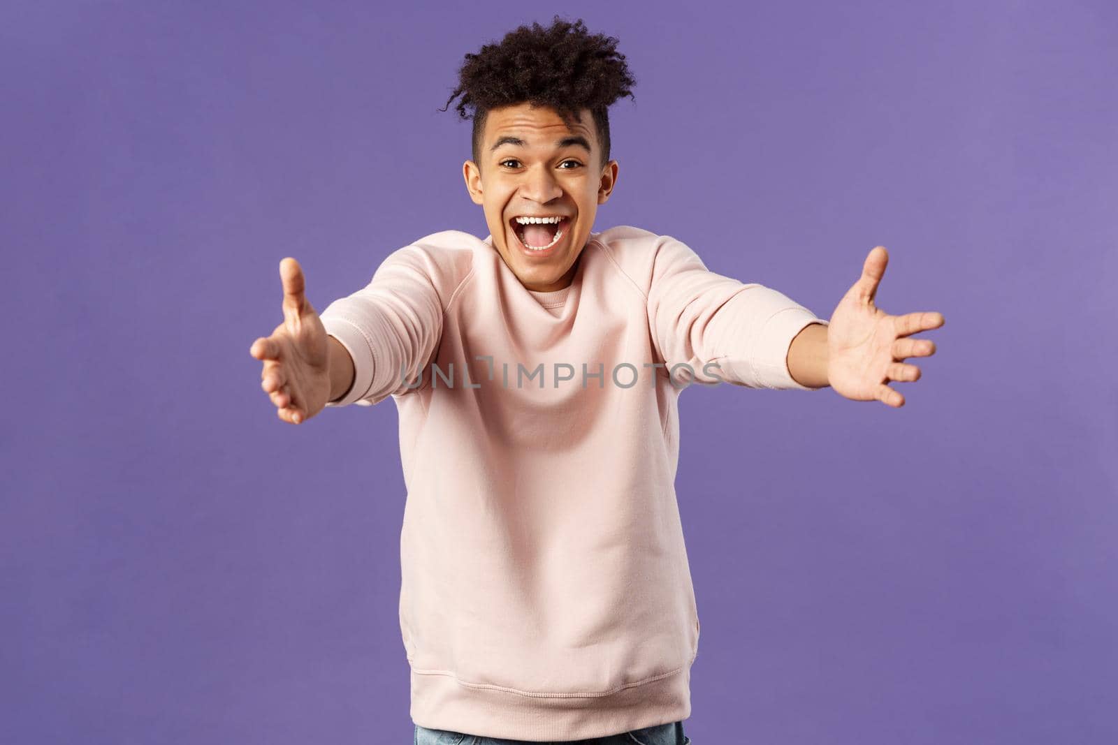 Portrait of happy charismatic, smiling hispanic man reaching hands to hug friend, laughing and grinning joyfully, meeting girlfriend at airport being cexcited finally see her, purple background.