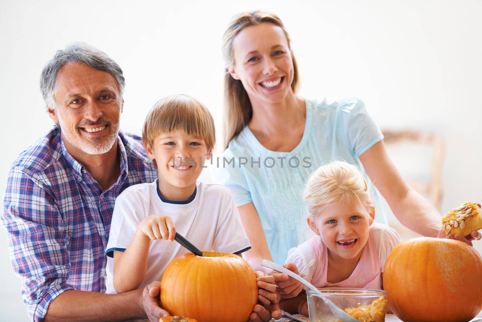 Family traditions. Portrait of a family of four hollowing out pumpkins for halloween. by YuriArcurs