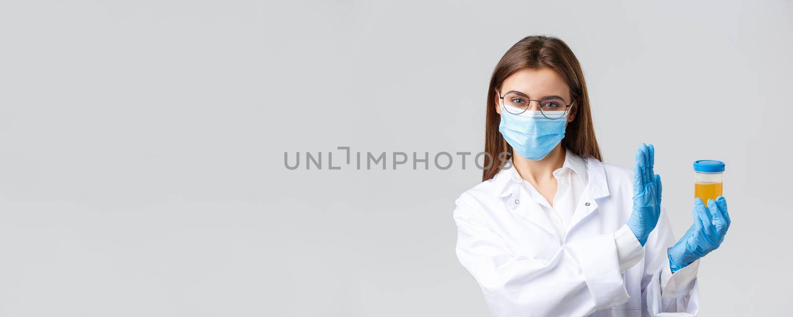 Covid-19, medical research, diagnosis, healthcare workers and quarantine concept. Doctor, intern in medical mask and gloves, lab clinic testing urine sample, show rejection and refusal gesture.