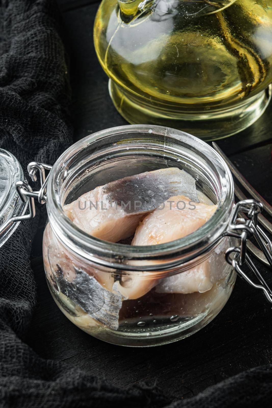 Sliced herring in oil marinated, on black wooden table background