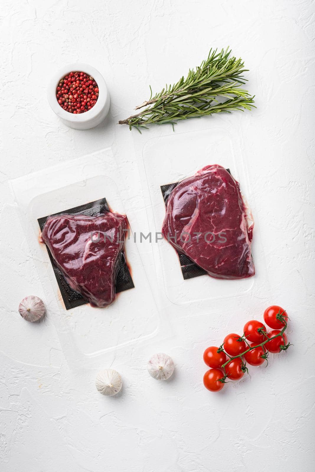 Beef steak vacuum sealed, on white stone table background, top view flat lay by Ilianesolenyi