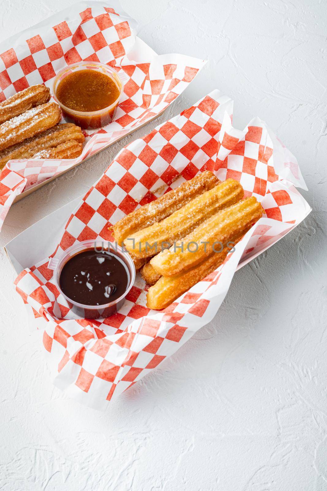 Spanish porras. Spanish food like spanish churros with chocolate, and caramel in paper tray, on white background