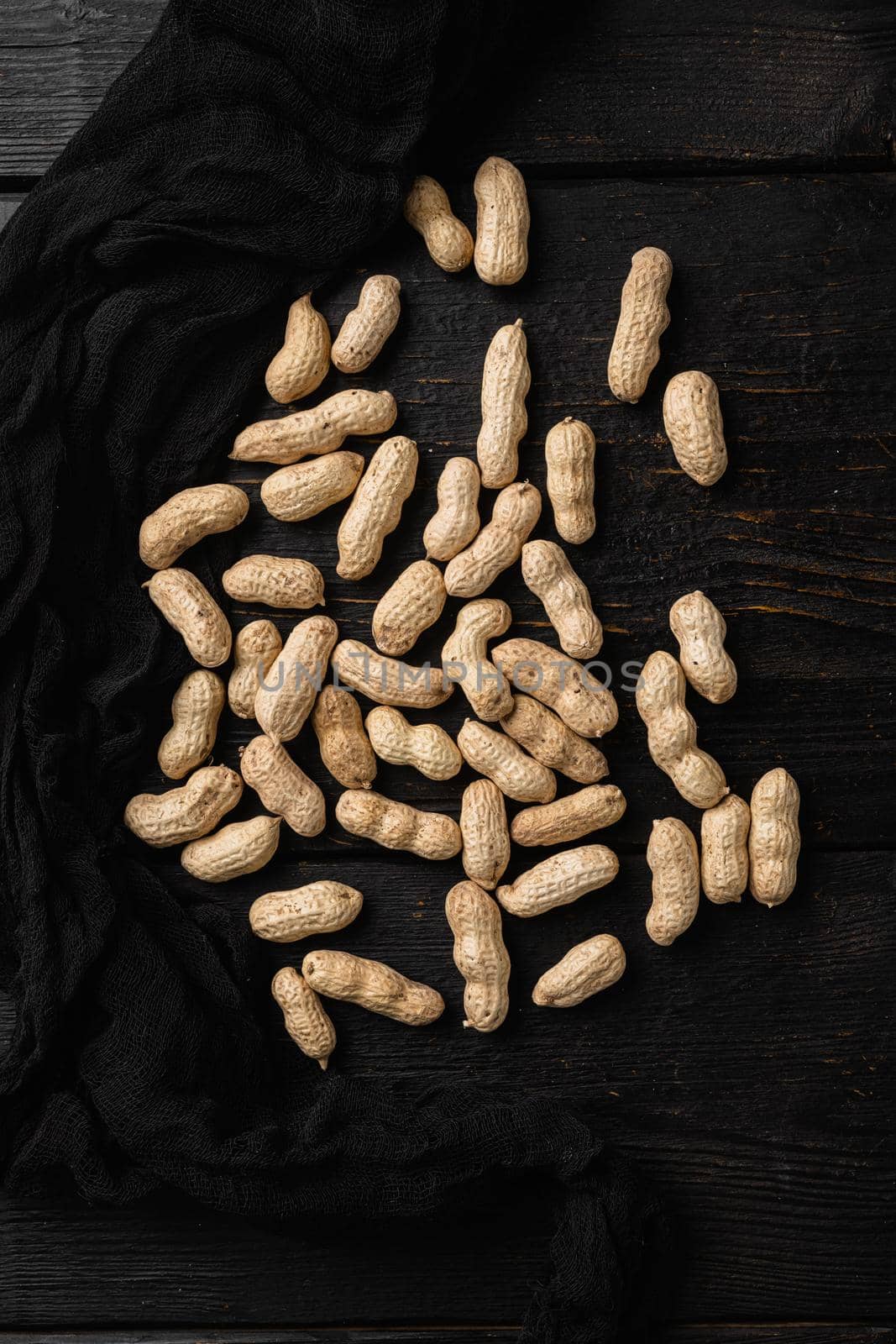 Whole peanut nuts, on black wooden table background, top view flat lay by Ilianesolenyi