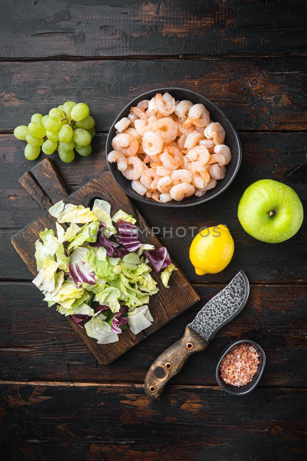 Seafood salad or appetizer shrimp and other ingredients, with sauce apple and grape, on old dark wooden table , top view flat lay by Ilianesolenyi