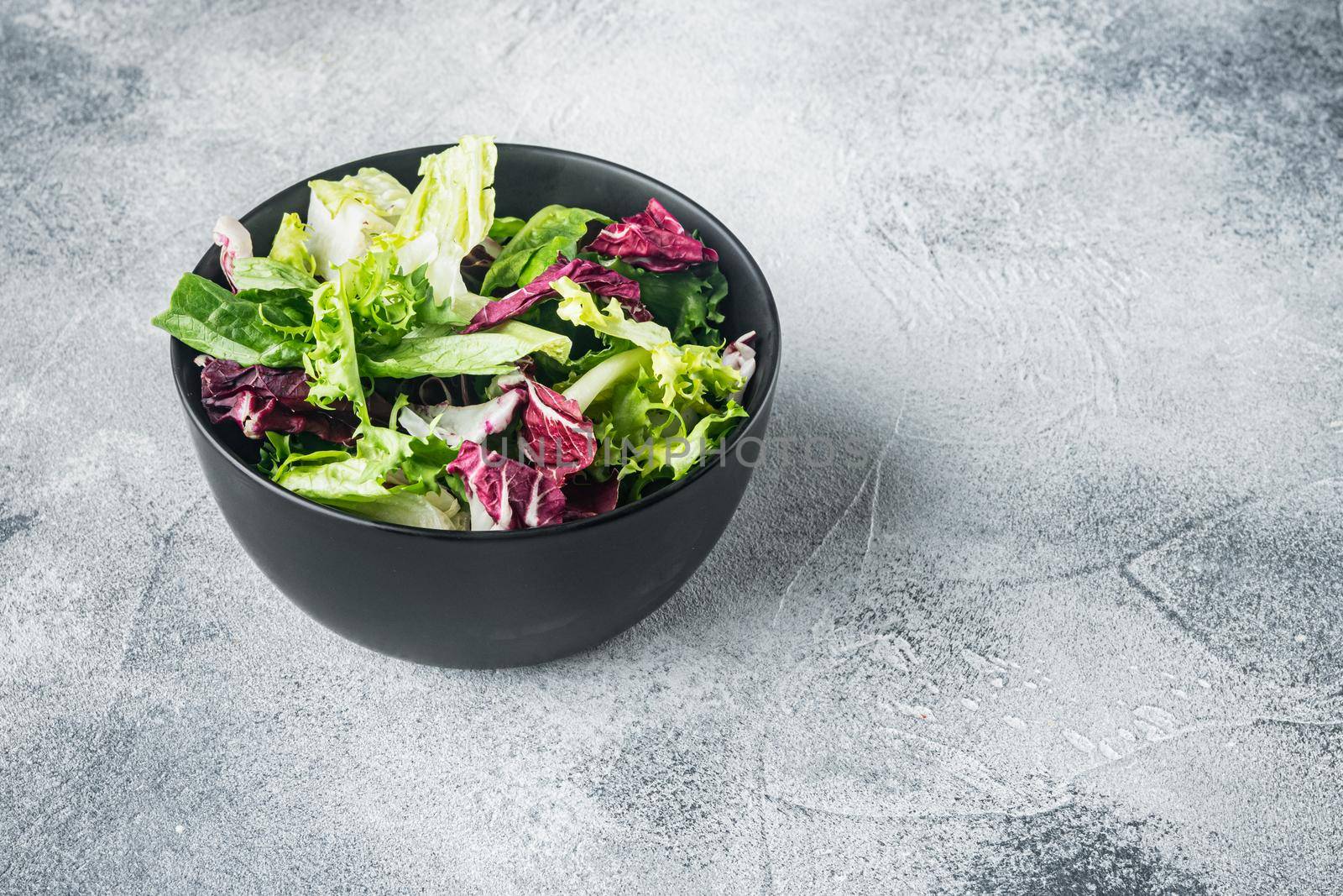 Bowls with mixed shredded salad lettuce fresh leaves, on gray background
