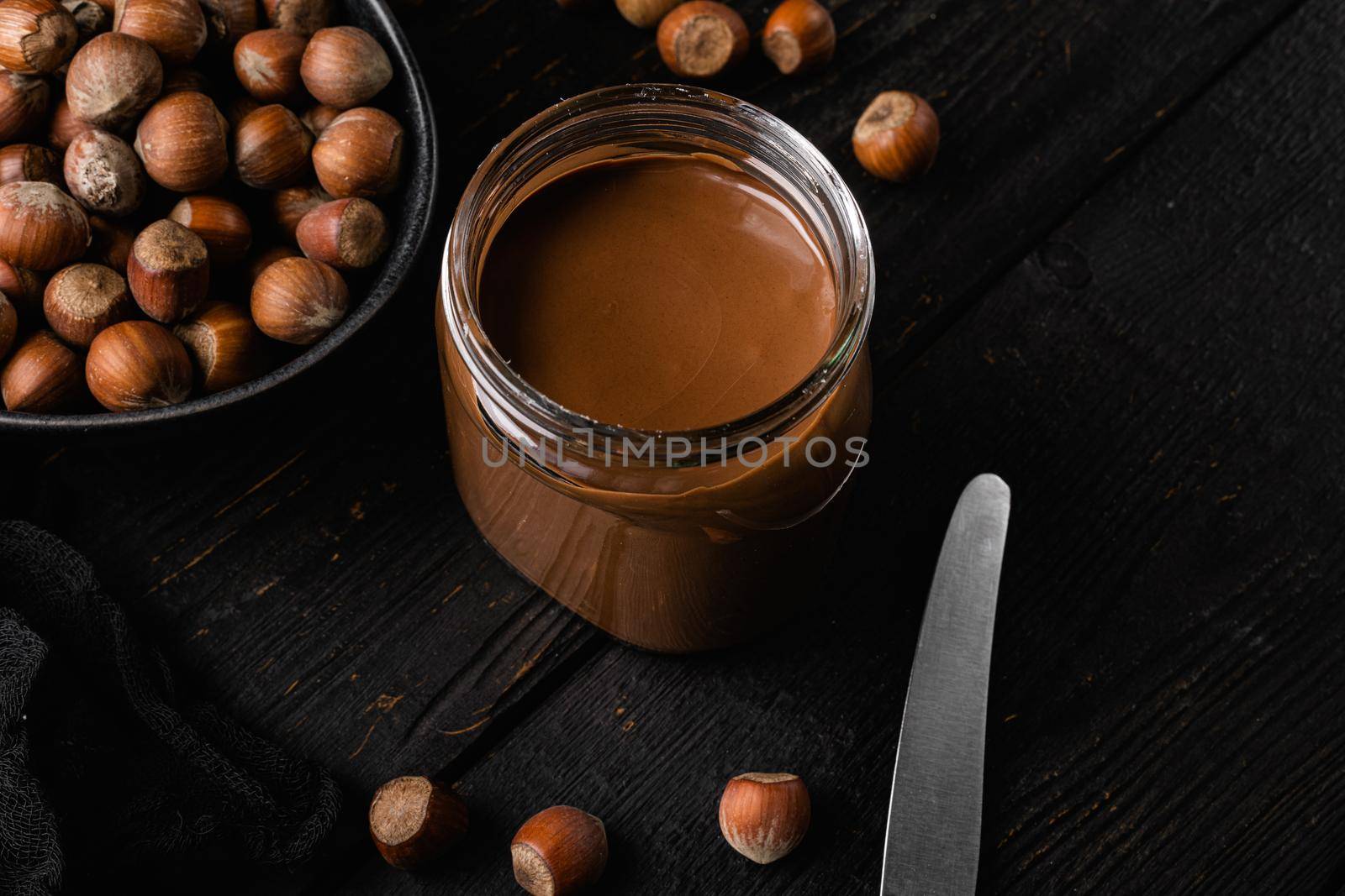 Chocolate spread or nougat cream with hazelnut set, on black wooden table background