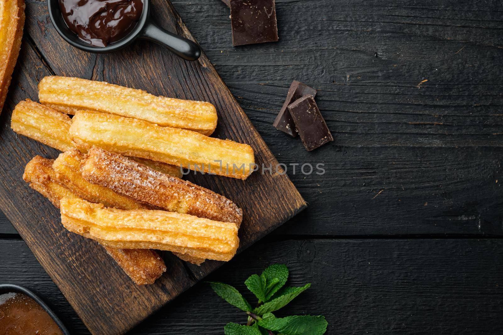Churros with caramel, Traditional Spanish cusine, on black wooden table background, top view flat lay with space for text, copyspace